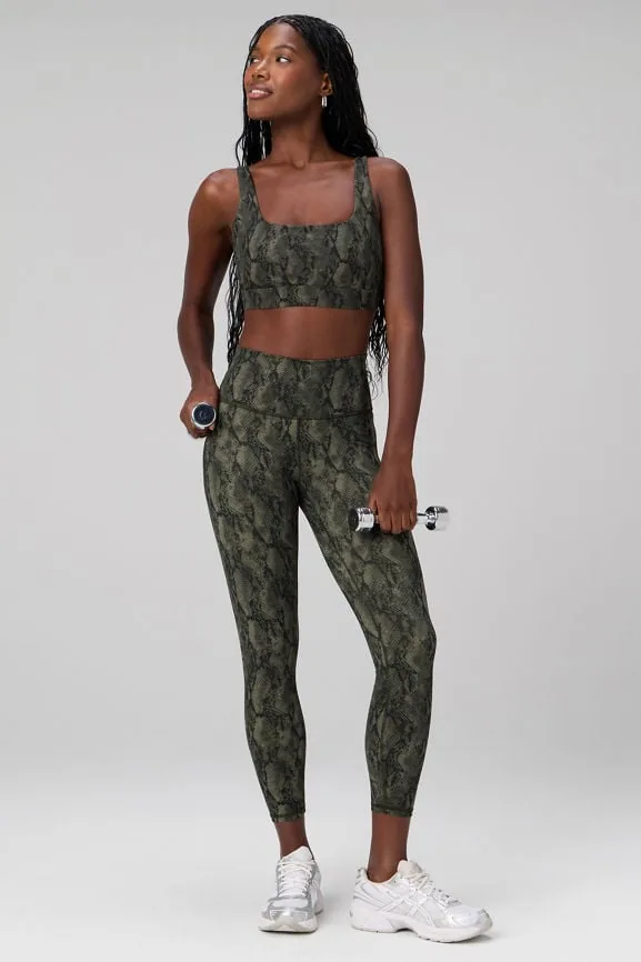 Frau in olivfarbener Leggings mit Schlangenmuster und dazu passendem Sport-BH, Ganzkörperaufnahme